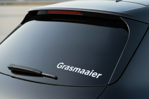 Witte Grasmaaier sticker close-up op achterruit van donkere auto